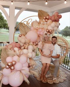 a man and woman standing next to each other on a porch with balloons in the air