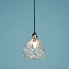 a clear glass light fixture hanging from a black cord against a blue sky background,