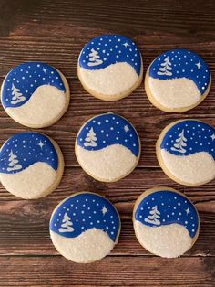 cookies decorated with blue and white frosting on a wooden surface, snow scene in the middle