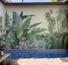 a mural on the side of a building in front of a pool with plants and flowers