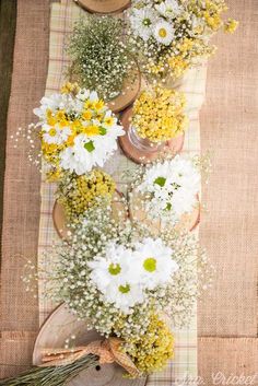 flowers are arranged in vases on a burlocked tablecloth with utensils