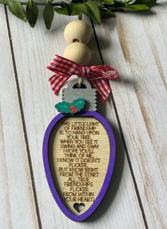 a wooden ornament with a purple heart and poem on it sitting next to some green leaves