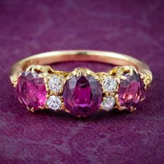 A gorgeous antique Victorian ring adorned with a trilogy of cherry-pink cushion cut rubies complemented by four twinkling old mine cut diamonds in between. The rubies have been tested as natural and are likely of Thailand or East African origin as detailed in the accompanying gem certification report. They weigh approx. 0.70ct and 0.80ct in the centre, with approx. 0.30ct of diamond.  Ruby is the birthstone of July and has long been associated with the heart due to its fiery pink/ red colouring Georgian Engagement Ring, Suffragette Jewellery, Antique Rings Victorian, Art Deco Jewelry Vintage, Pink Cushion, Ruby Diamond Ring, Tanzanite Engagement Ring, Victorian Engagement Rings, Victorian Ring