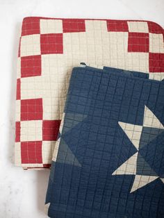 two quilts with stars on them sitting next to each other, one blue and the other red