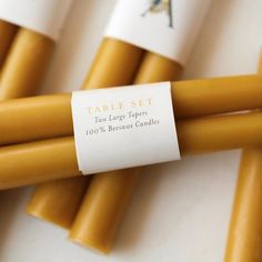 four yellow candles with labels on them sitting on a white counter top next to each other