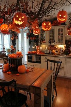 a kitchen decorated for halloween with pumpkins hanging from the ceiling and decorations on the table