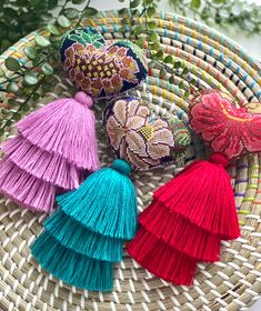 four tasseled purses sitting on top of a woven basket next to plants