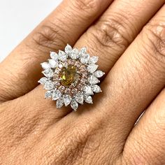 The Blossoms Diamond Cocktail Ring is uniquely floral and dazzling. With a orangey brown diamond center and a pink diamond halo, all surrounded with marquise and pear shape diamond radiating outwards, the ring is a mesmerizing jewel. Center Diamond Shape: CushionCenter Diamond Weight: 0.84 ct Diamond Color: Orangey BrownDiamond Clarity: SI Side Diamonds Shapes: Round, Pear Shape & MarquiseSide Diamonds Weight: 2.25 ctSide Diamonds Color: H & Fancy PinkSide Diamonds Clarity: VS Metal: 18K White & Diamonds Shapes, Diamond Cocktail Ring, Diamond Cocktail Rings, Brown Diamond, Pear Shaped Diamond, Diamond Color, Diamond Halo, Diamond Shape, Pink Diamond