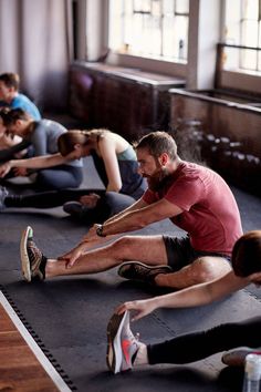 a group of people sitting on the floor doing stretching exercises with their feet in the air