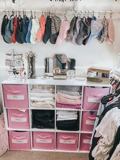 an organized closet with pink drawers and lots of clothes hanging on the wall above it