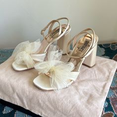 a pair of white high heeled shoes sitting on top of a blanket