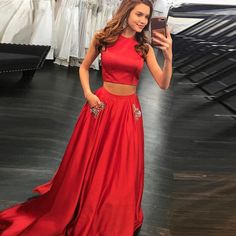 a woman in a red two piece dress taking a selfie with her cell phone