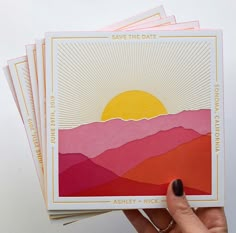 a person holding up five cards with mountains in the background and sun rising over them