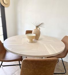 a white table with brown chairs and a vase on it's centerpiece in the middle