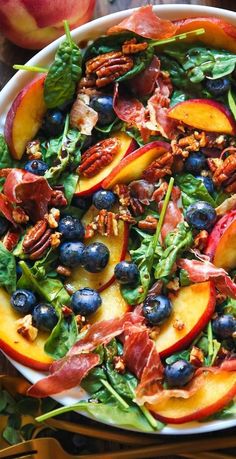 a salad with peaches, blueberries and pecans in it on a plate