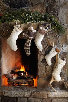 christmas stockings hanging from the fireplace with candles in front of them and a bottle of wine next to it