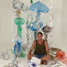 a woman sitting on the ground in front of an assortment of blown glass items and decorations