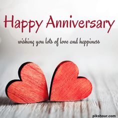 two red hearts sitting next to each other on top of a wooden table with the caption happy anniversary wishing you lots of love and happiness