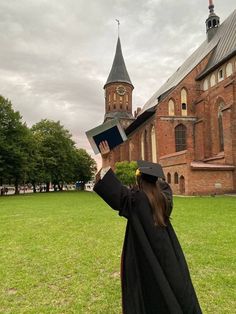 a woman in graduation gown holding up an open book with a tower on top of it