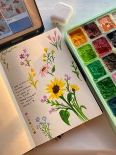 an open watercolor book next to a cell phone