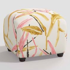 a white and pink ottoman covered in gold leaf print on top of a gray floor