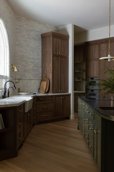 a large kitchen with wooden cabinets and an arched window in the center, along with dark wood flooring