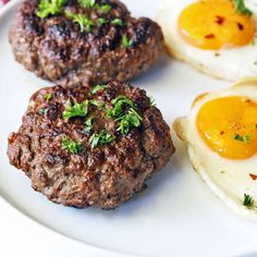 three eggs and two hamburger patties on a plate