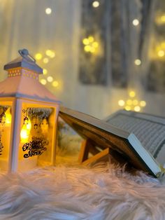 an open book sitting on top of a table next to a lit up candle holder