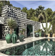 some green vases sitting on the side of a swimming pool next to a building