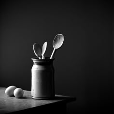 black and white photograph of utensils in a jar with spoons on a table