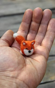 a hand holding a tiny stuffed animal in it's palm