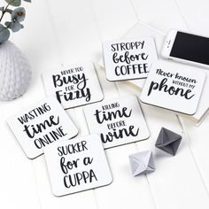 four coasters with different sayings on them next to a vase and phone holder