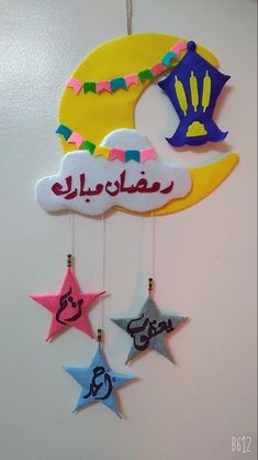 a crescent and stars with arabic writing hanging from the side of a white wall in a room