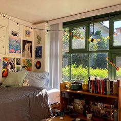 a bed sitting under a window next to a book shelf with lots of books on it