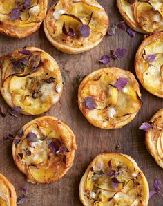 some food that is on top of a wooden table with purple and green leaves around it