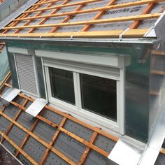 the roof of a house being built with wooden boards and windows on top of it