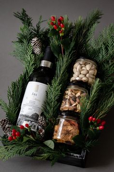 a bottle of wine sitting on top of a wooden box filled with nuts and pine cones