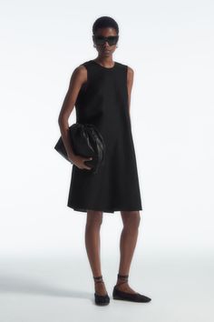 This simple mini dress rings true to the considered design ethos at COS. Offered in a perennial black hue, it's styled in a clean A-line silhouette and has an enthraling twist detail that frames the V-back. It is crafted from a TENCEL™ Lyocell and linen blend that's light in balmy weather. Relaxed fitSide seam pocketsTENCEL™ is a trademark of Lenzing AG. TENCEL™ Lyocell is made from renewable wood sources, using a process that recycles 99% of all chemicals and water  Shell: 77% TENCEL™ Lyocell, 23% Linen. Excluding trims / Machine wash Back length of size 6 is 95.3cm / Model wears a size 6 Simple Mini Dress, Glamorous Fashion, Dress Rings, Wool Dress, New Arrival Dress, Simple Dresses, V Shape, Mini Black Dress, Minimalist Fashion