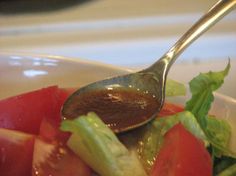 a salad with tomatoes, lettuce and tomato slices on it is being spooned