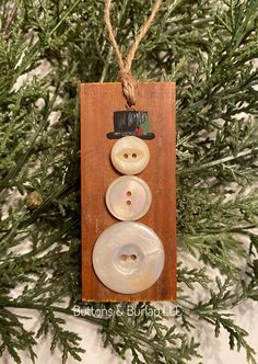 a wooden ornament with two buttons and a top hat on it hanging from a tree