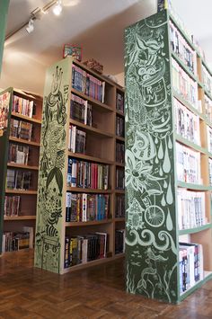 two tall bookshelves with drawings on them in a library