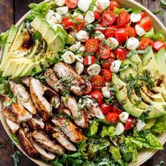 a salad with chicken, tomatoes, avocado and lettuce on it