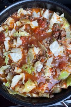 a skillet filled with cabbage, meat and sauce