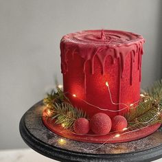 a red cake with icing and christmas lights on it sitting on a black plate