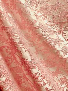 pink and white fabric with intricate designs on it