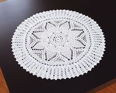 a white doily sitting on top of a black table next to a wooden floor