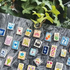 many different colored tiles on a table next to some plants