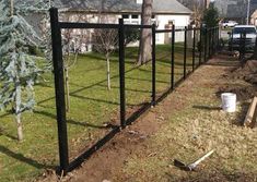 a black fence is in the yard next to a tree and some dirt on the ground