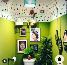 a bathroom with green walls and pictures on the wall above the toilet is decorated with plants