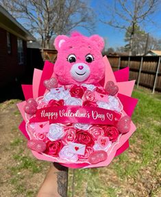 a pink teddy bear holding a valentine's day bouquet